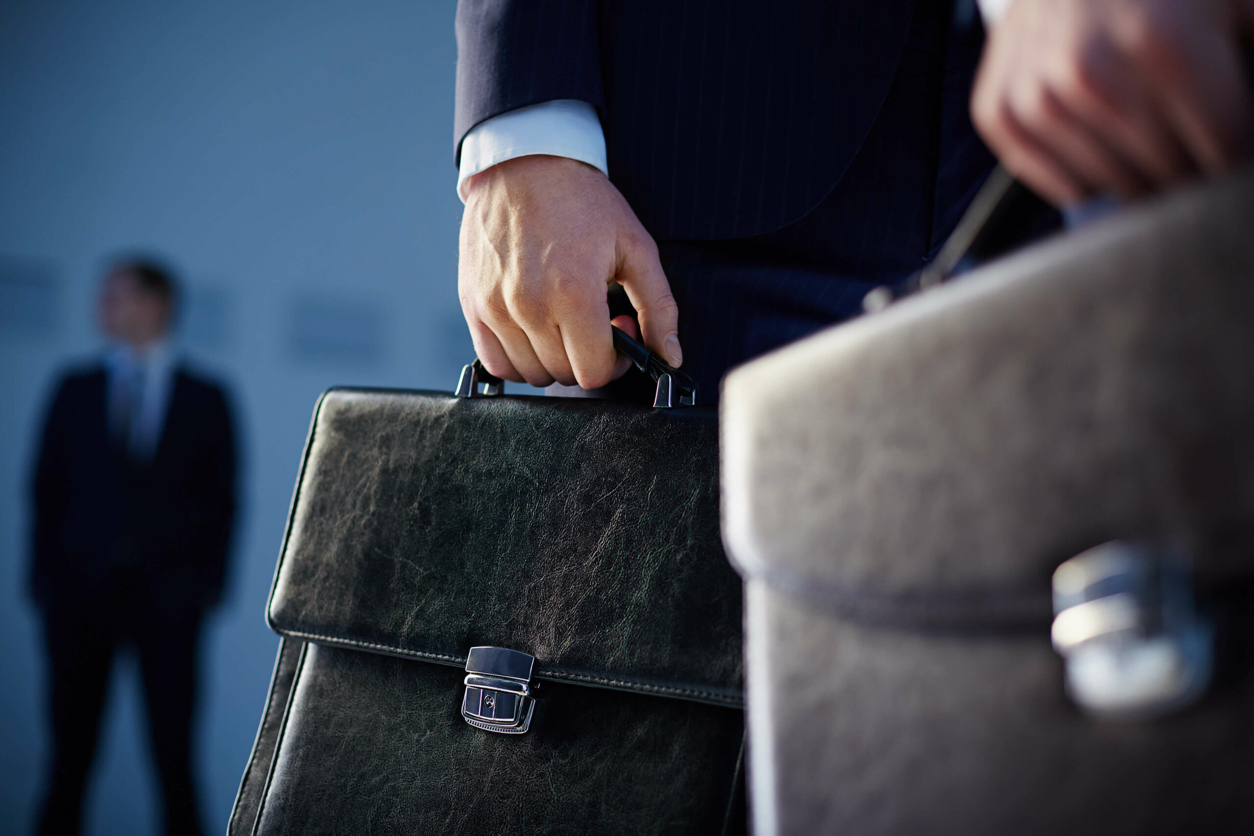 cropped-image-of-business-partners-carrying-briefcases-on-the-foreground-while-their-c-SBI-300726224